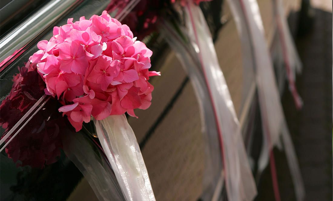 Sargschmuck bestehend aus rosafarbener Blüten und weißen Schärpen