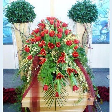 Sarg mit üppiger Blumendekoration in weiß und rot sowie grünem Beiwerk und roten Schärpen