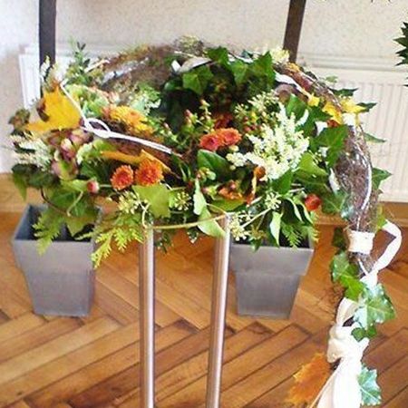 Vorbereitung für die Präsentation einer Urne durch einen Blumenkranz geschmückt mit verschiedenfarbigen Blüten primär in weiß, orange und rötlich gehaltenen Farben
