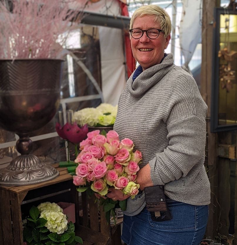 Beate Ossenkemper mit einem Strauß rosaroter Rosen in den Händen